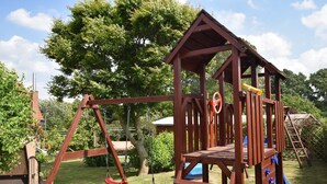 Una struttura di legno con scivolo e altalene in un giardino.