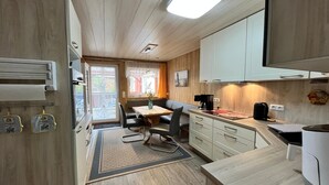Una cucina compatta con zona pranzo, mobili in legno e finestra con tende.