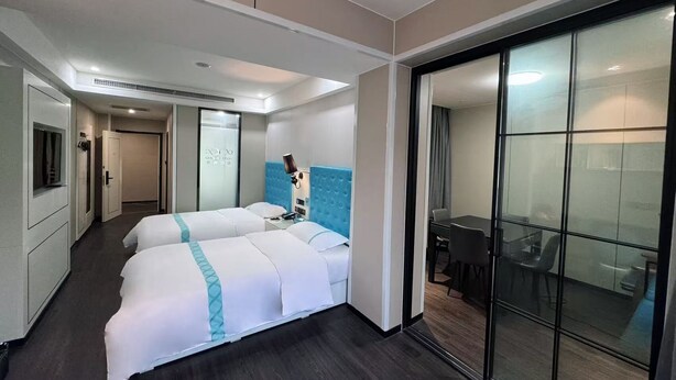 A hotel room with two beds, a desk, a chair, a TV, and a sliding glass door to a balcony. - Xana Lite Hotel Gu'an Train Station (Shiyan)