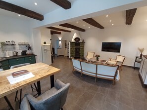 Eine geräumige Küche mit modernen Geräten, ein Essbereich mit Holztisch und Stühlen sowie eine gemütliche Sitzecke mit Sofa und Sesseln.