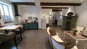 A modern kitchen with a dining area, a fireplace, and a seating area with a bench and chairs. - Müllerstube im Müllerhaus (Lübeck)