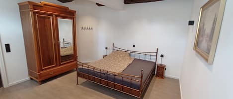 Un dormitorio con un armario de madera, una cama con cubrecama estampado y una mesita de noche.