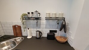 A kitchen with a stainless steel sink, a kettle, a toaster, and a basket on the counter. - Müllerstube im Müllerhaus (Lübeck)