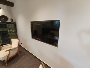 Ein Zimmer mit einem großen Flachbildfernseher an der Wand, einem Holzstuhl und einem gekachelten Kamin.
