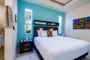 A bedroom with a bed, a nightstand, a mirror, and a wall with colorful artwork. - Modern V399 Studio | Walk to Beach, Dining & Night 1BD Condo for rent in Old Tow (Puerto Vallarta)