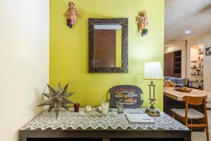 A room with a green wall, a mirror, a table with a lace tablecloth, a star decoration, a candle, a lamp, and a framed picture. - Modern V399 Studio | Walk to Beach, Dining & Night 1BD Condo for rent in Old Tow (Puerto Vallarta)
