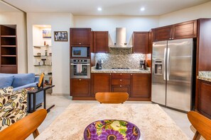 A compact kitchen with wooden cabinets, a stainless steel refrigerator, a microwave, and a gas stove. - Modern V399 Studio | Walk to Beach, Dining & Night 1BD Condo for rent in Old Tow (Puerto Vallarta)
