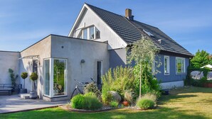 Une maison moderne dotée d’un grand patio, d’un vélo et d’un jardin bien entretenu.