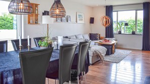 Un salon moderne avec un coin repas, de grandes fenêtres et une vue sur la verdure.