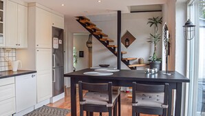 Une cuisine moderne avec des meubles blancs, une table à manger noire et un escalier en bois.