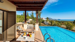 A poolside area with a table set for breakfast, a pool, and a view of the landscape. - Villa Daphne in Inverness (Rhodes)