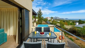 A balcony with a table set for breakfast, a pool, and a view of the landscape. - Villa Daphne in Inverness (Rhodes)