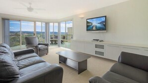 Un salon moderne doté d’un téléviseur à écran plat, de canapés en cuir, d’une table basse et offrant une vue sur l’extérieur.