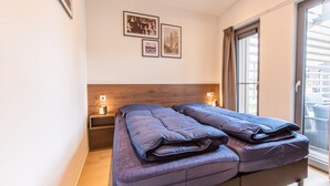 A bedroom with a double bed, a nightstand with a lamp, and a sliding glass door leading to a balcony. - Cube Split Hottub 6 (Enkhuizen)