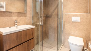 A modern bathroom with a glass-enclosed shower, a wooden vanity, and a white toilet. - Cube Split Hottub 6 (Enkhuizen)