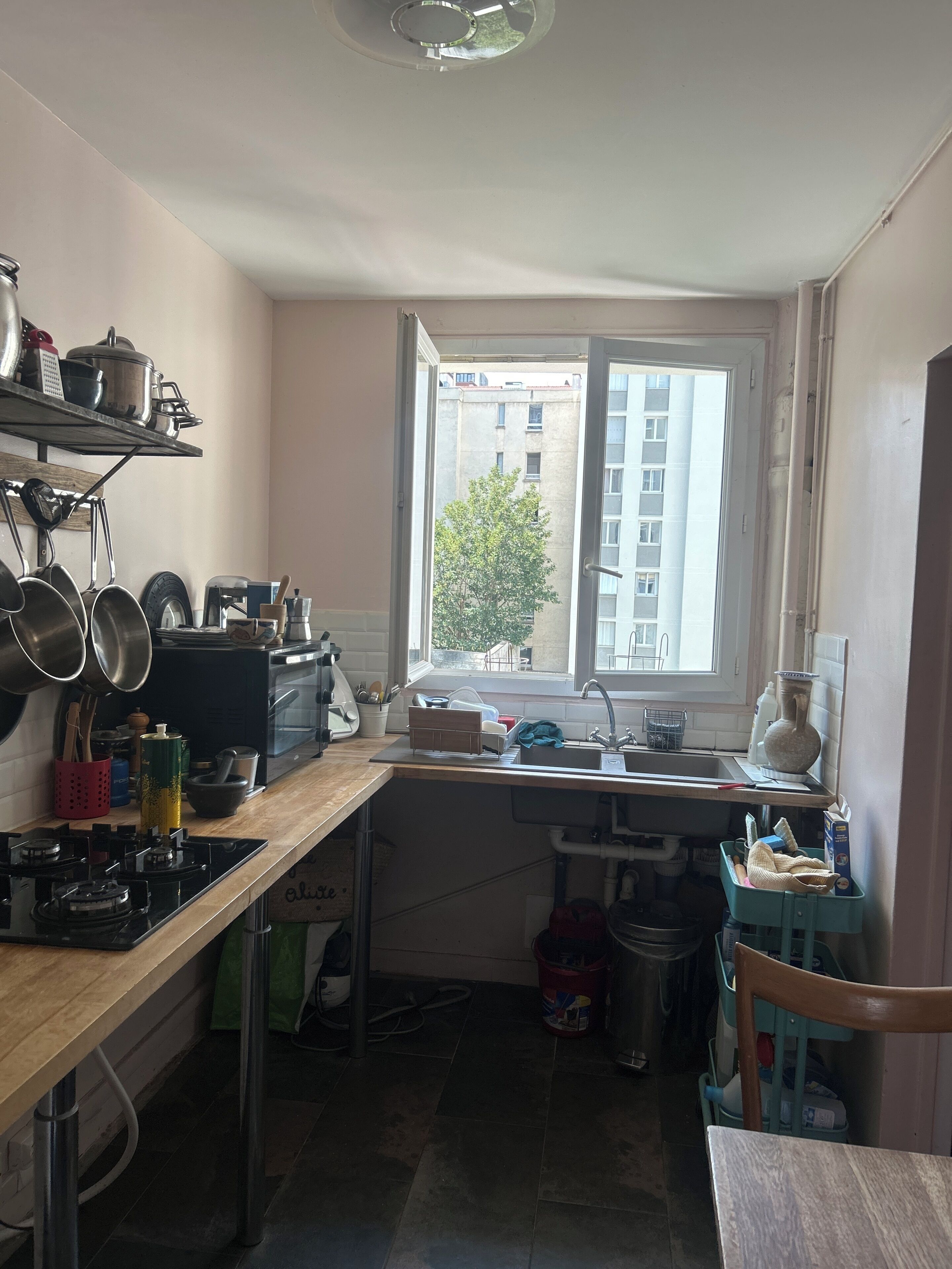 Une cuisine de taille réduite, dotée d’une fenêtre, d’une cuisinière et de divers ustensiles.
