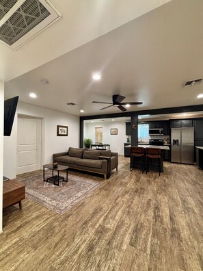A modern living room with a sofa, coffee table, and a dining area with chairs and a kitchen in the background. - Downtown Phoenix Home w/ Pool- Near Airport! (Phoenix)