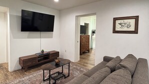 Un salon doté d’un grand téléviseur à écran plat, d’un meuble de rangement en bois, d’un canapé et d’un tableau encadré accroché au mur.