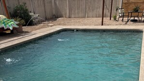 Une piscine aux eaux cristallines, dotée d’une terrasse en bois et d’un petit jardin.