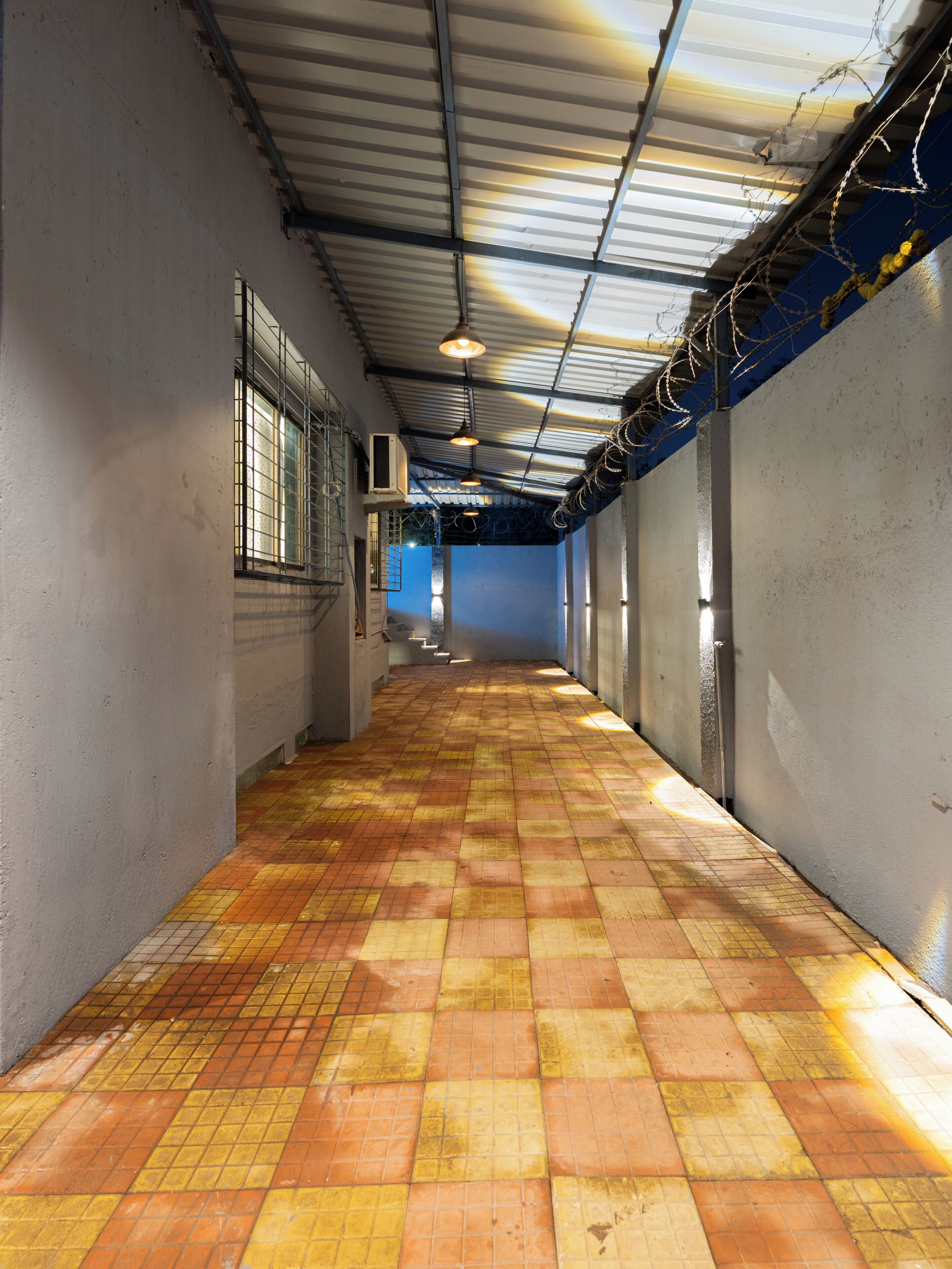 A corridor with tiled flooring, metal beams, and a ceiling with lights.
