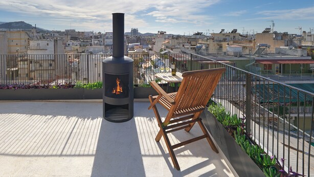 Une terrasse sur le toit équipée d’un poêle à bois, d’une table et d’une chaise.