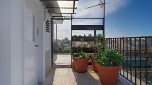 Un balcon agrémenté de plantes en pot, une vue sur le paysage urbain et un ciel dégagé.