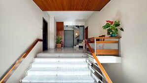 Un escalier moderne avec une finition en bois, une rampe en verre et des plantes en pot sur le palier.