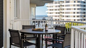 A balcony with a round table, chairs, a bottle, and a plate of food. - Coastal Rooftop Escape Mooloolaba - Walk to Beach (Mooloolaba Region)