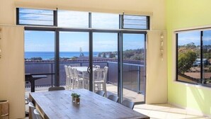 Ein Zimmer mit einer großen Schiebeglasdoor zum Balkon mit Meerblick.