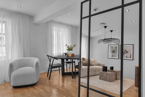 Un salon moderne avec un fauteuil gris, une table à manger avec des chaises, un canapé et une table basse.
