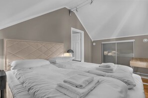 Une chambre à coucher avec un grand lit, une tête de lit, une table de chevet, une lampe et une armoire.