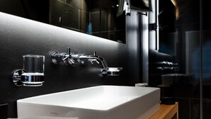 A modern bathroom with a white sink, chrome faucet, and a glass of water.