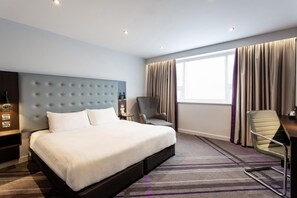 A hotel room with a large bed, a desk, a chair, a nightstand, and a window with curtains. - Premier Inn Manchester City Centre - Northern Quarter (Manchester)