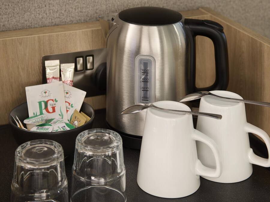 A kitchen counter with a kettle, mugs, and packets of PG tips tea.