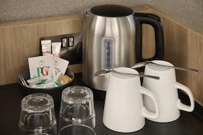 Una encimera de cocina con una tetera, tazas y paquetes de té PG tips.