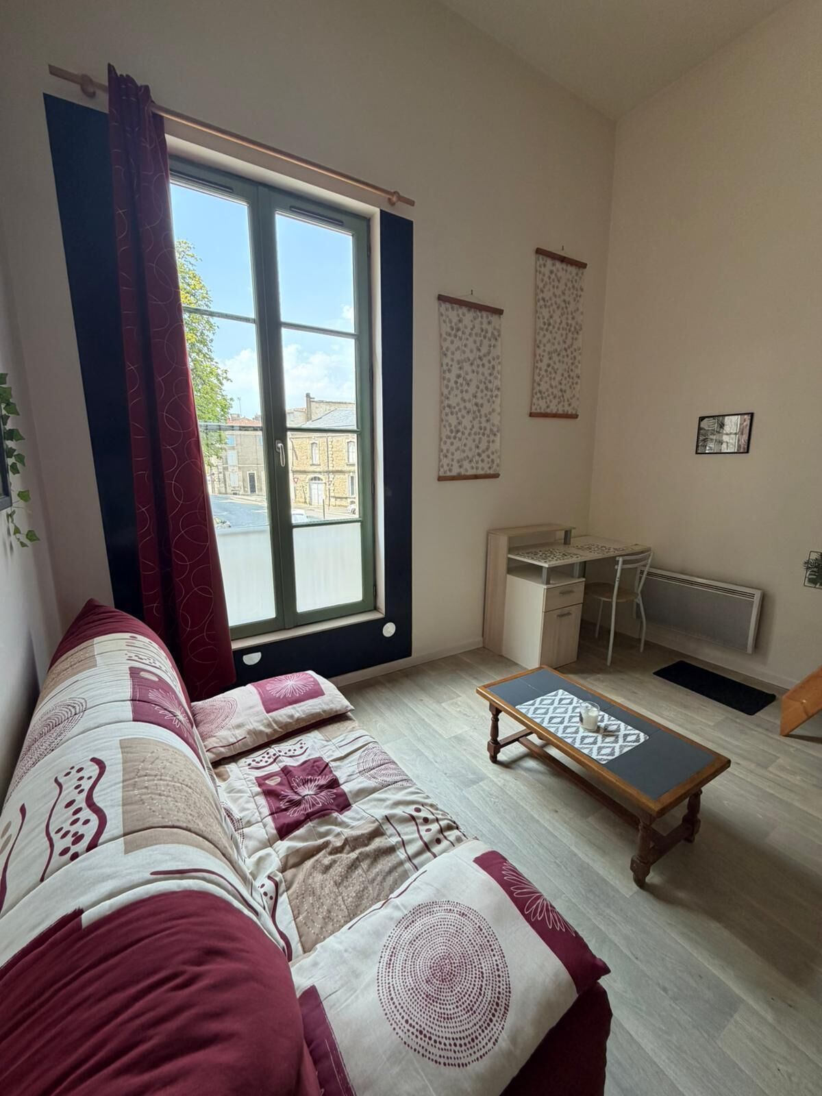Een kamer met een bank, een klein tafeltje, een bureau en een radiator.