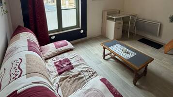 Een kamer met een bank, een klein tafeltje, een bureau en een radiator.