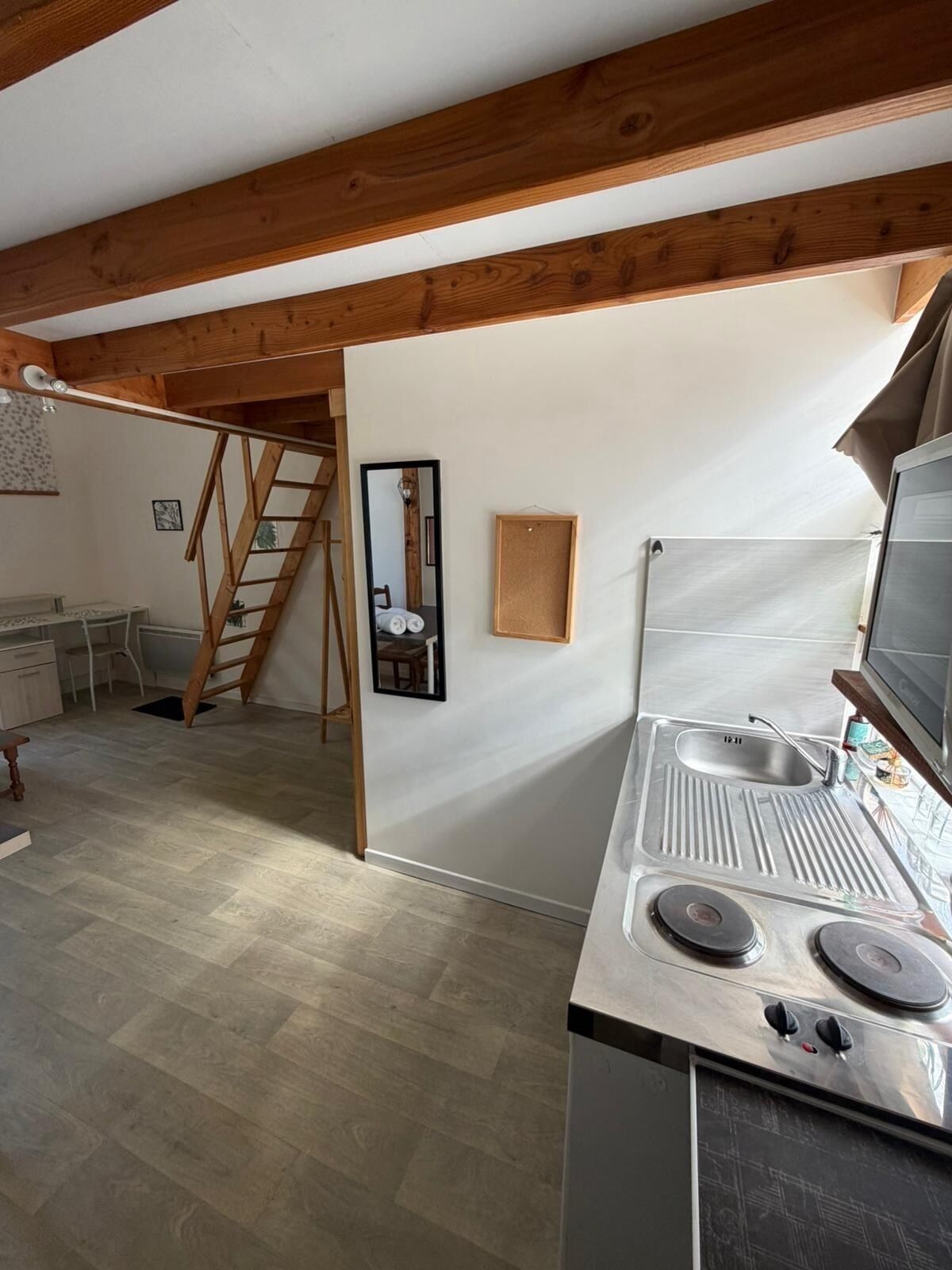 A kitchen with a stove, sink, and wooden beams.