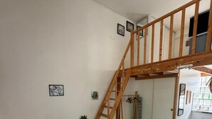 Ein geräumiges Lofts Apartment mit einer Holztreppe, einer Essecke und einer Küche.