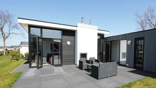 Une maison moderne dotée d’un patio, d’une porte-fenêtre coulissante et de mobilier d’extérieur.