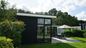 Une maison moderne dotée d’un patio, d’un coin repas et d’une grande fenêtre.