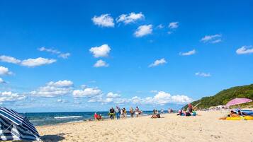 A beach with people, umbrellas, and a clear sky.