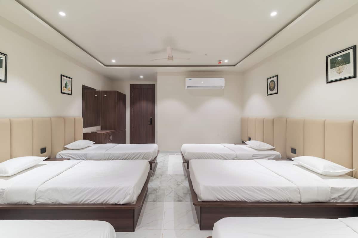A hotel room with four beds, a ceiling fan, an air conditioning unit, and a door leading to a bathroom.
