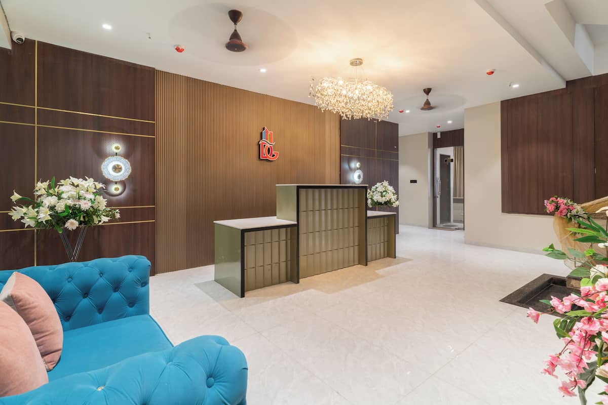 A modern reception area with a blue sofa, a reception desk, and a decorative chandelier.