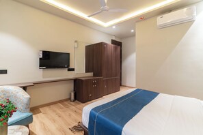 A bedroom with a bed, a wardrobe, a TV, and a ceiling fan. - Grand Dularia (Nagpur)