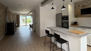 Eine moderne Küche mit einer zentralen Kochinsel, Pendelleuchten und Blick ins Freie.