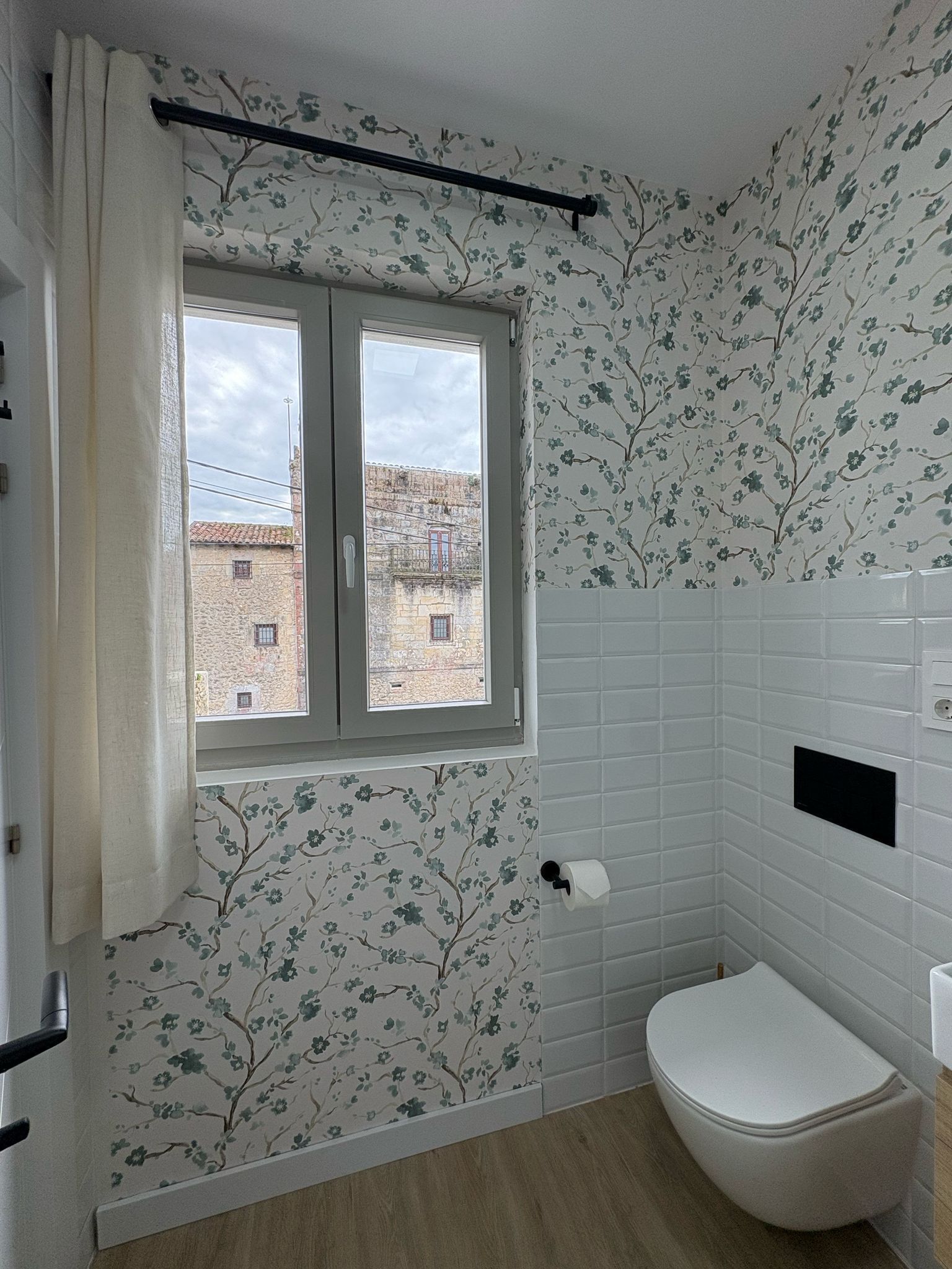 Um banheiro com janela, paredes azulejadas em branco e vaso sanit ário.