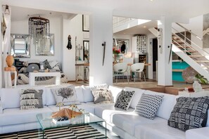 Een moderne woonkamer met een witte bank, glazen salontafel en decoratieve accessoires.