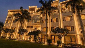 Un hotel de varios pisos con balcones, palmeras y una fachada bien iluminada.