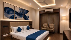 Una habitación de hotel moderna con una cama grande, mesitas de noche, un escritorio, una silla y un ventilador de techo.
